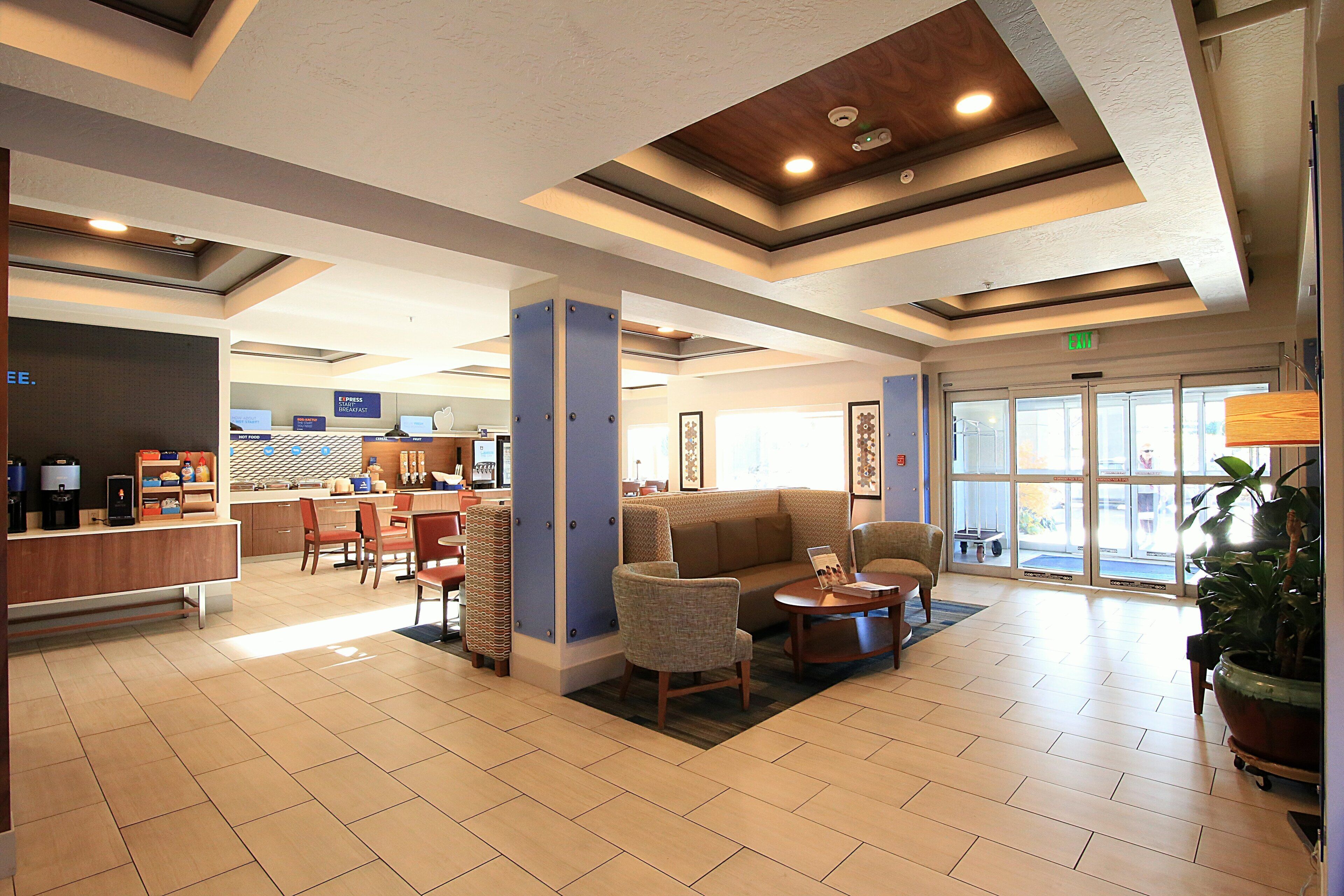 A hotel lobby with a reception desk, seating area, and a large window.