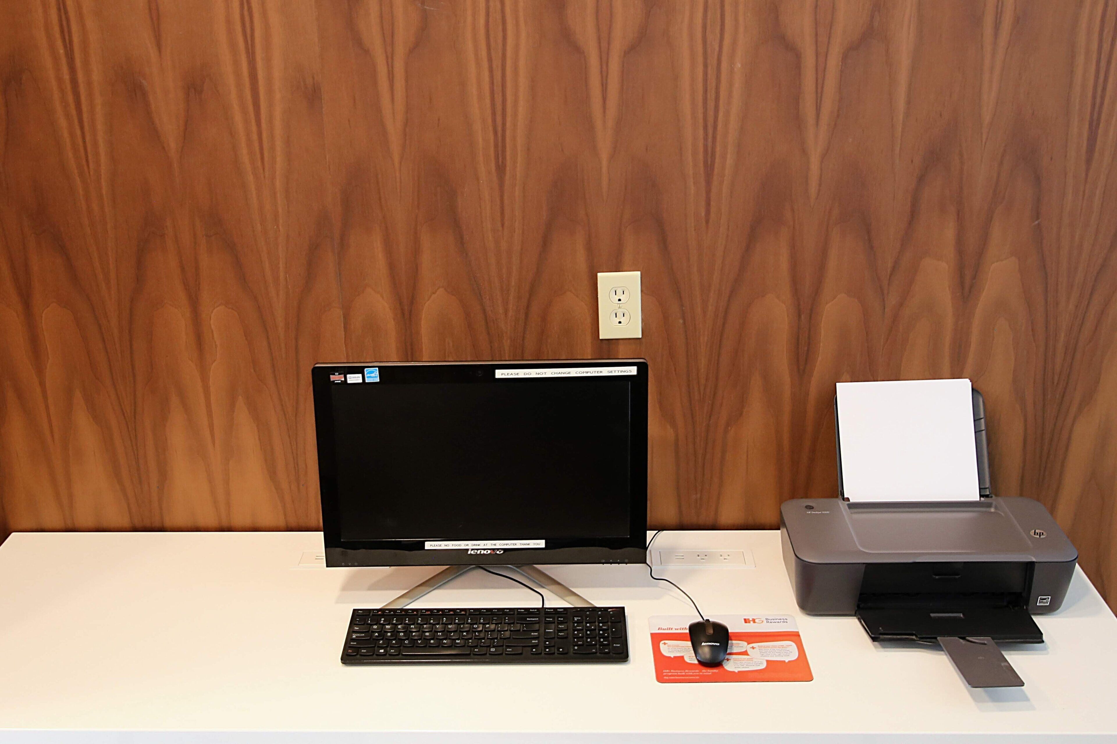 A desk with a computer monitor, keyboard, mouse, and printer.