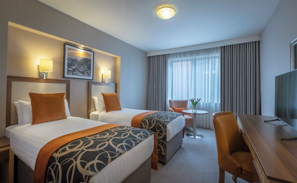 A hotel room with two beds, a desk, a chair, a TV, and a window with curtains. - Clayton Hotel Belfast City (Belfast)