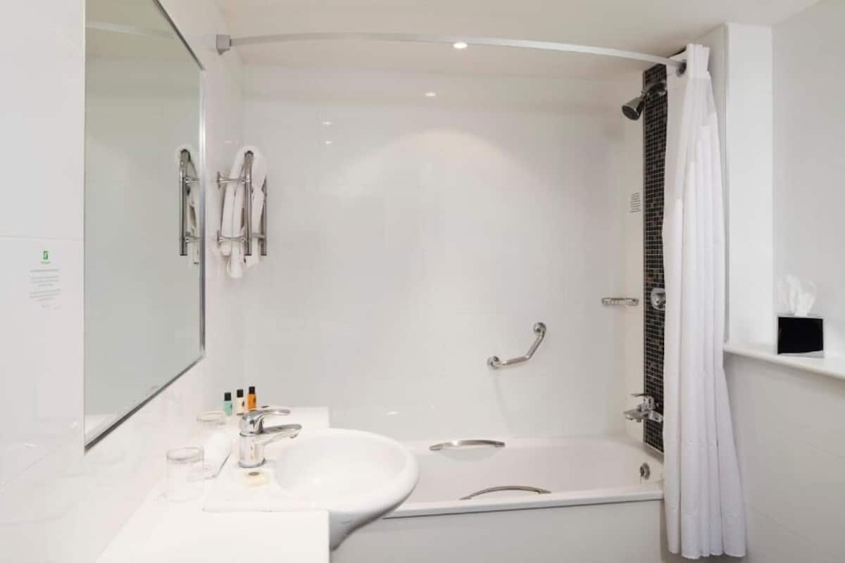 A modern bathroom with a white sink, mirror, and a walk-in shower.