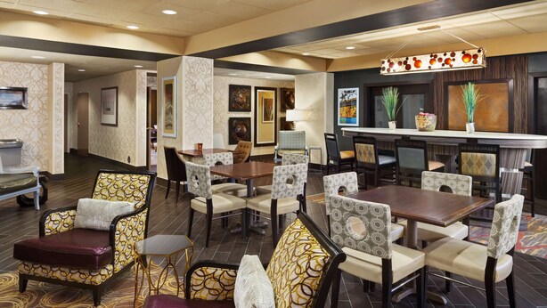 Un vestíbulo de hotel con varias zonas de estar, incluyendo un bar y una recepción.