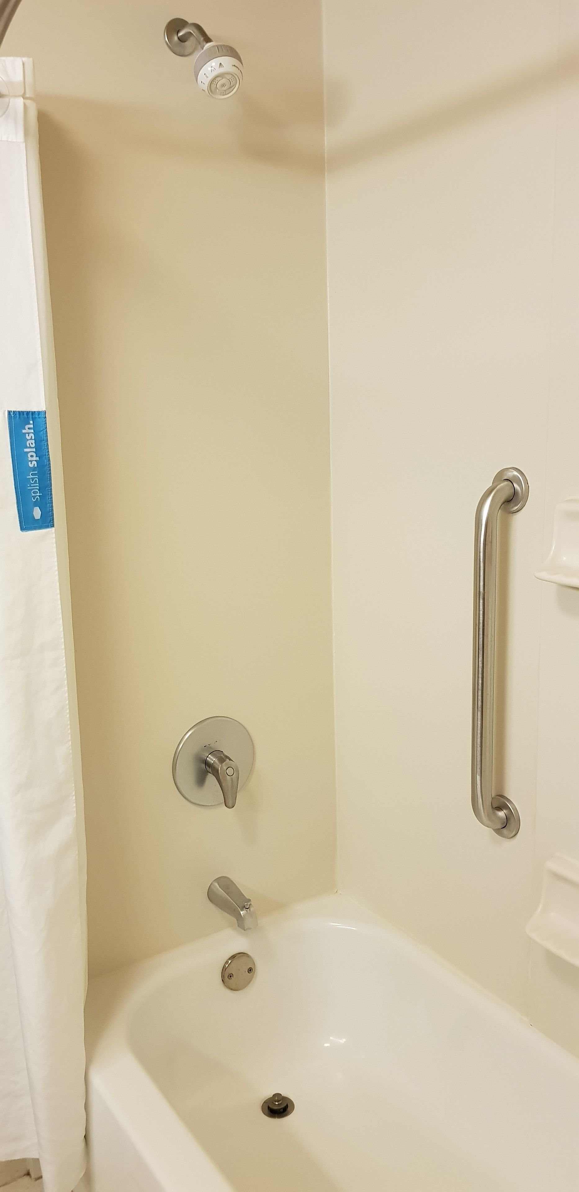 Un bagno con vasca, doccetta, rubinetto e mancorrente.