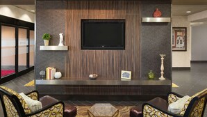 Un hall con mostrador de recepción, zona de estar y televisor de pantalla plana en la pared.