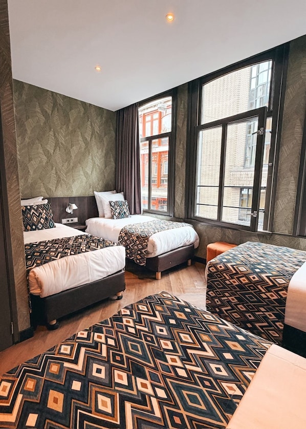 A hotel room with two beds, a large window, and a patterned rug.