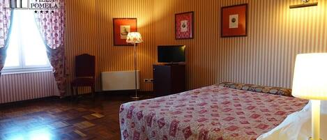 Una habitación de hotel con una cama, un televisor, un escritorio y una silla.