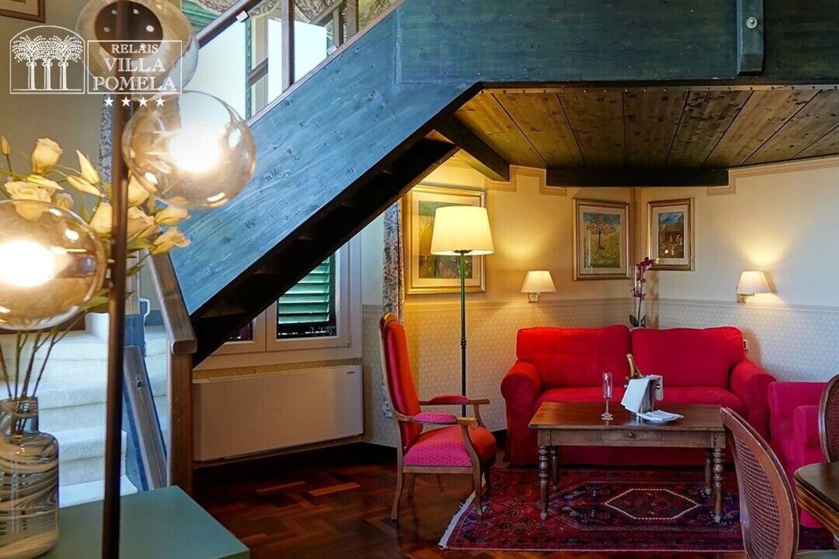 A cozy living room with a red sofa, a wooden coffee table, and a staircase leading to an upper level.