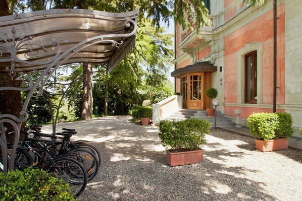 A courtyard with bicycles, a gazebo, and a building with a red facade. - Relais Villa Pomela (Novi Ligure)