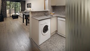 A compact kitchen with a washing machine, a sink, and a countertop. - Aparthotel Hispanos 7 Suiza (Barcelona)