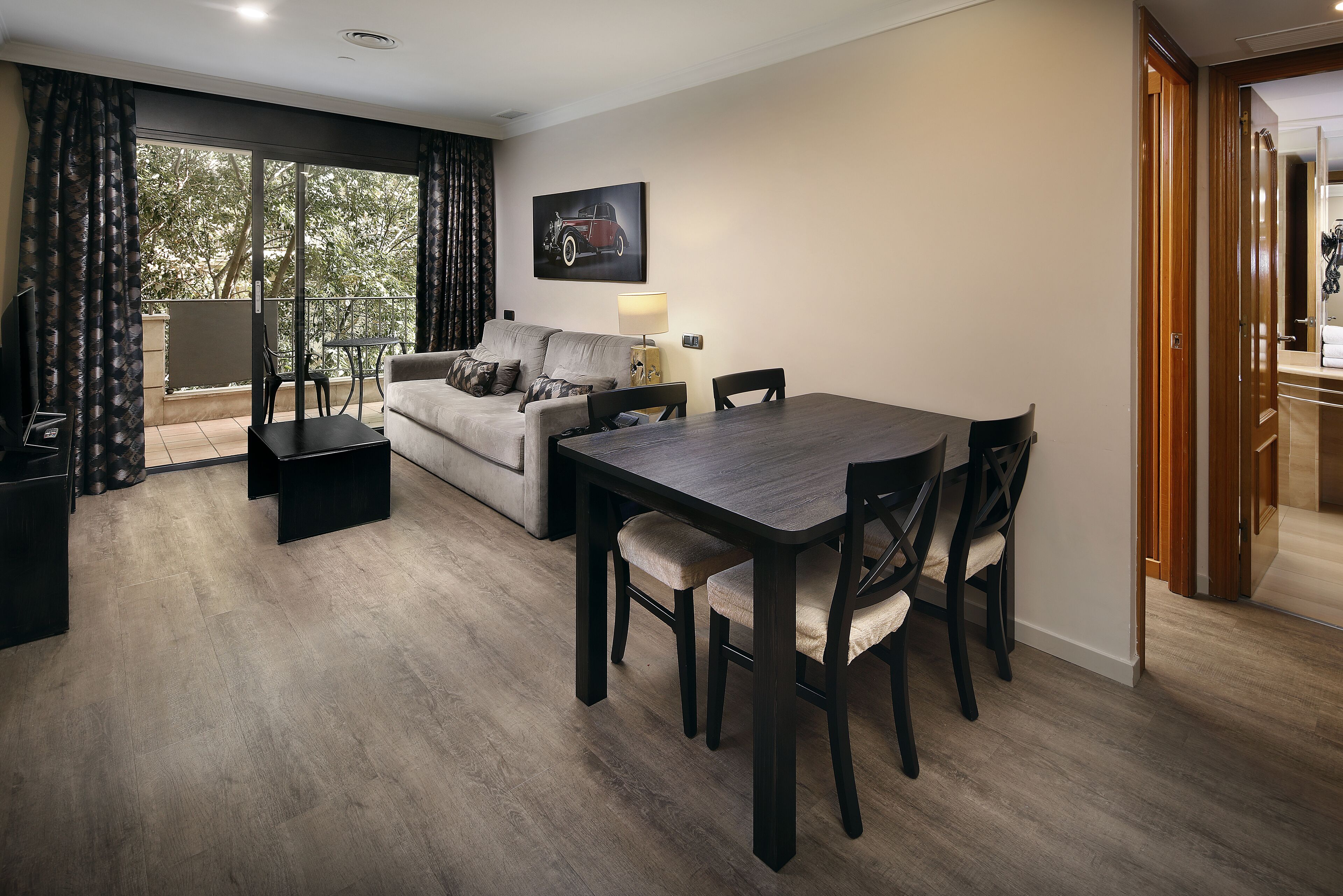 A modern living room with a sofa, a dining table with chairs, a TV, and a balcony with curtains.