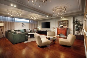 Una sala de estar moderna con un sofá modular, dos sillones, una mesa de centro y un televisor de pantalla plana montado en la pared.