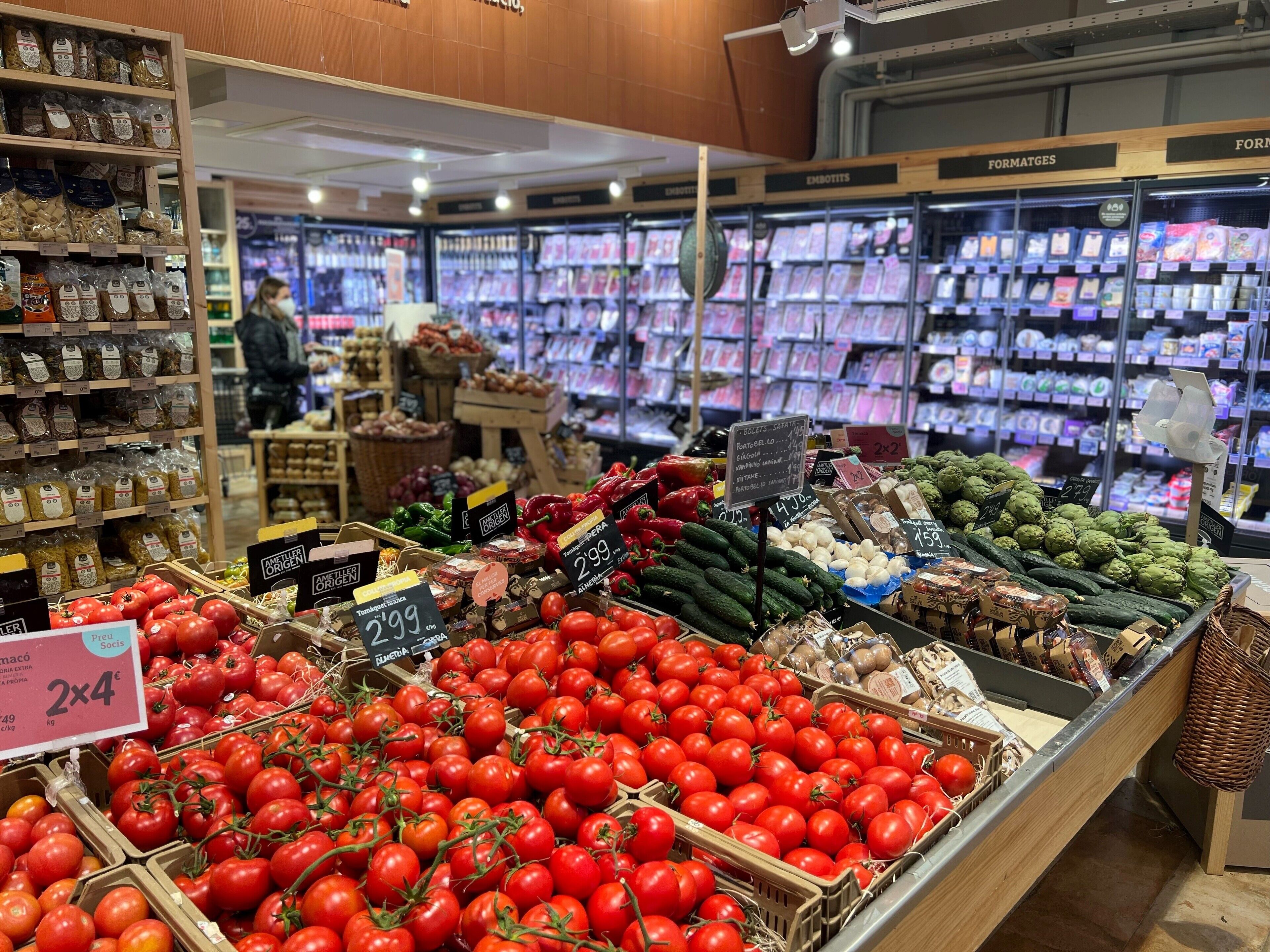 Ein Lebensmittelgeschäft mit frischem Obst und Gemüse, darunter Tomaten und Artischocken, und Regalen voller verpackter Waren.