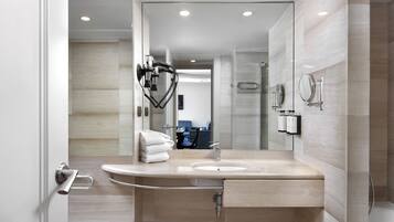Une salle de bain moderne avec un lavabo aux lignes courbes, un porte-serviettes et un miroir.