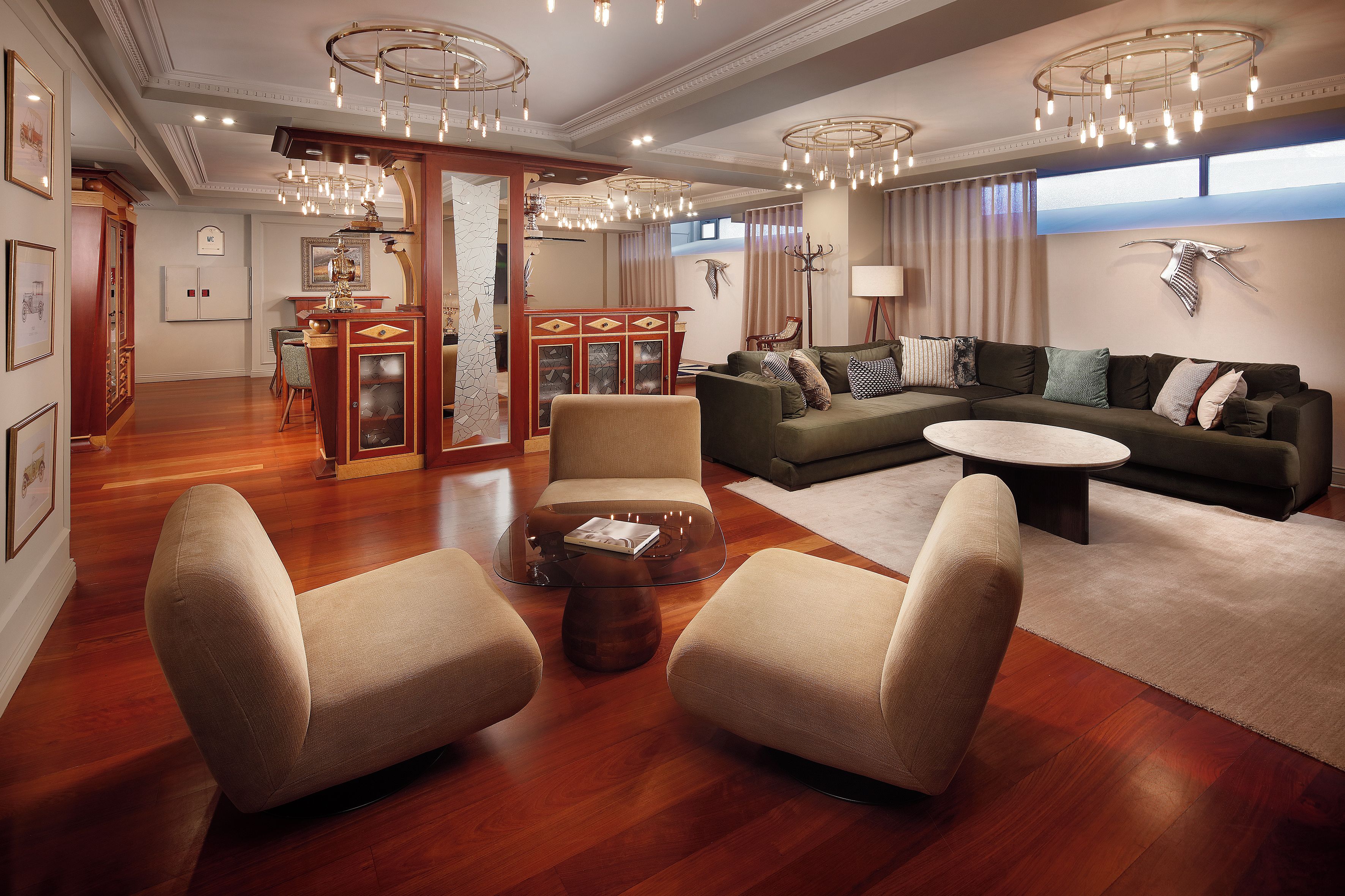 A spacious living room with a sectional sofa, two armchairs, a coffee table, and a chandelier.