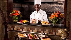 Un chef en una cocina profesional con salpicadero de azulejos, encimera pulida y centros de mesa florales.
