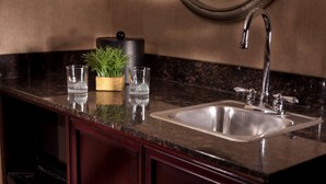 Una cocina con encimera de granito, pileta de acero inoxidable y armarios de madera.