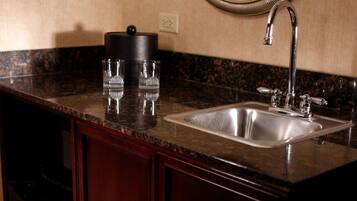 A kitchen with a granite countertop, stainless steel sink, and wooden cabinets.