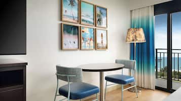 A modern hotel room with a balcony, a TV, and artwork on the wall.