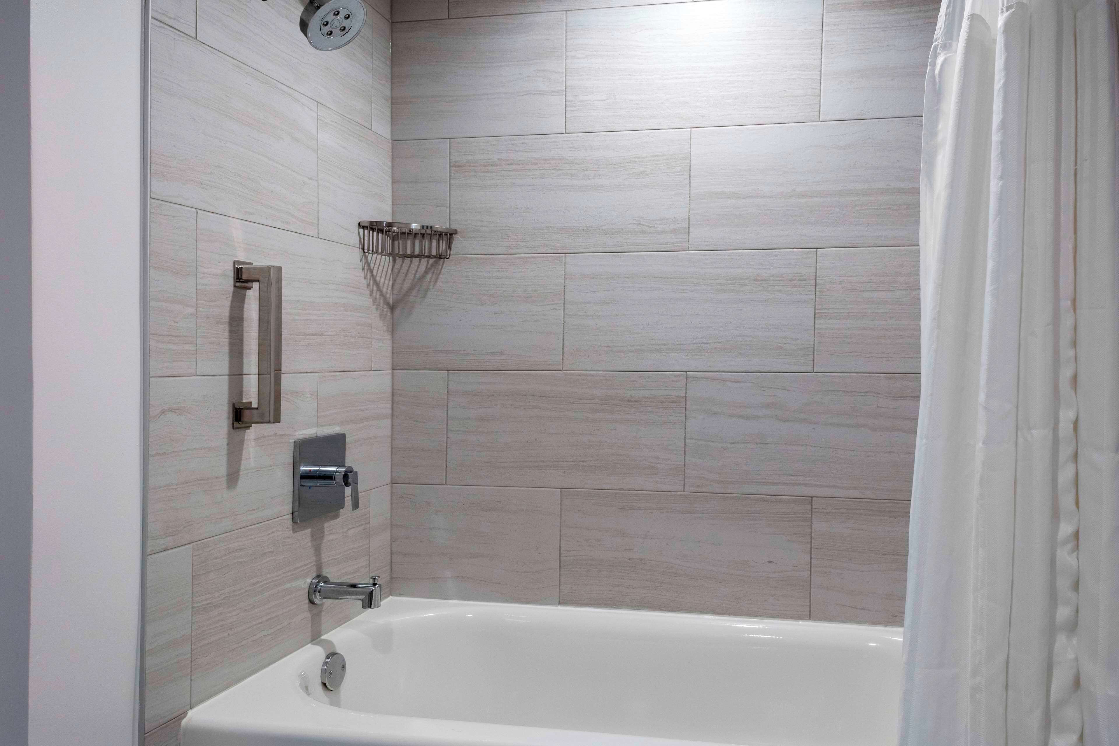 A modern bathroom with a bathtub, a showerhead, and a towel rack.