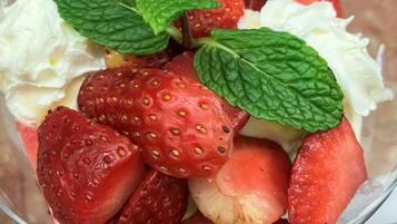 A dessert bowl with strawberries, mint leaves, and whipped cream.