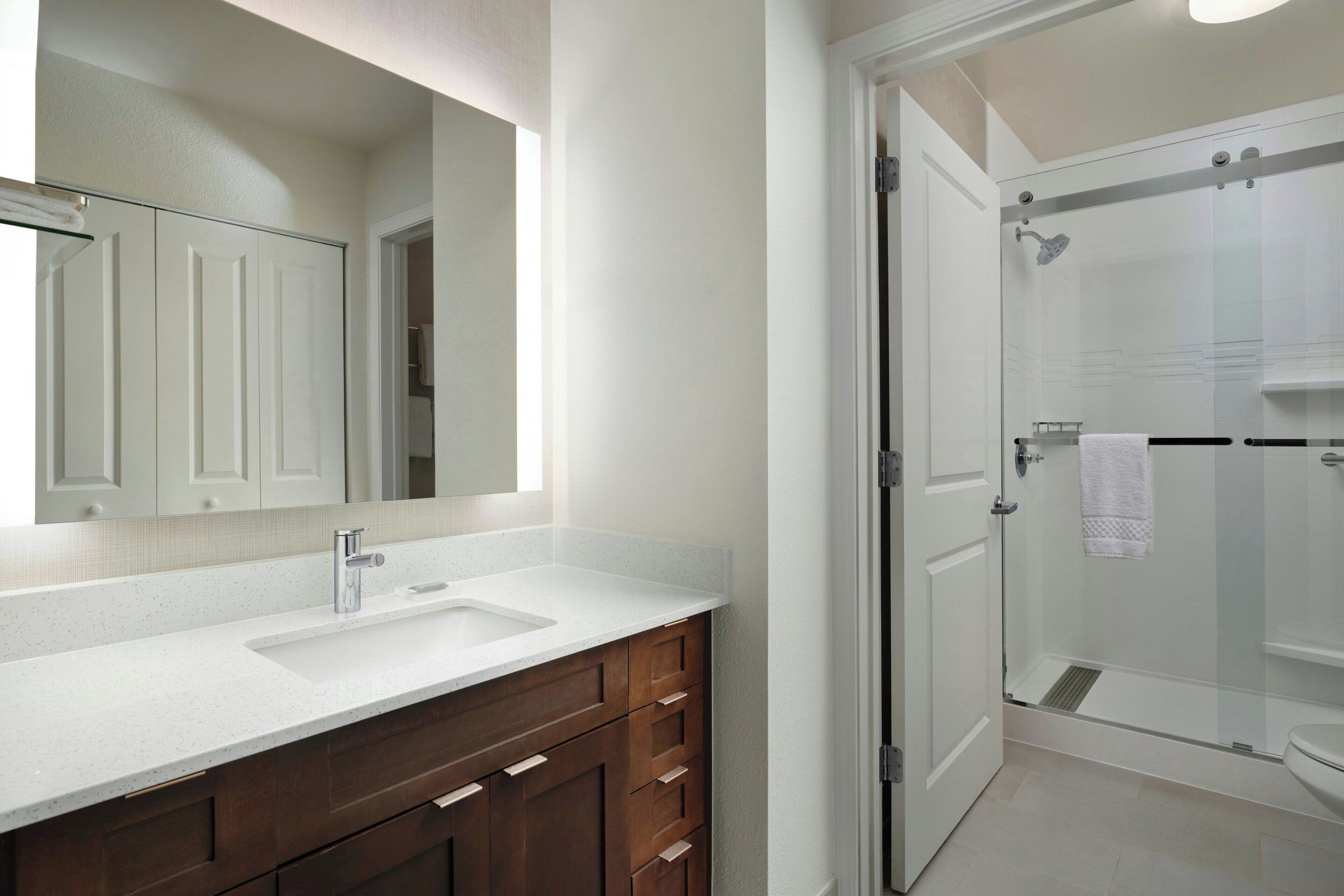 A bathroom with a white vanity, a large mirror, and a glass shower enclosure.