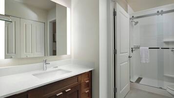 A bathroom with a white vanity, a large mirror, and a glass shower enclosure.