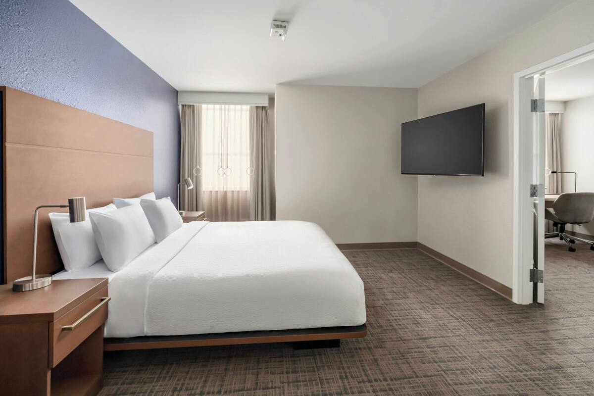 A hotel room with a bed, a TV, a desk, and a chair.