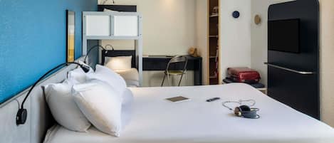 Habitación de hotel con cama, escritorio, silla, televisor y armario.