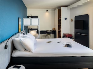 A hotel room with a bed, a desk, a chair, a TV, and a wardrobe. - ibis Auch (Auch)