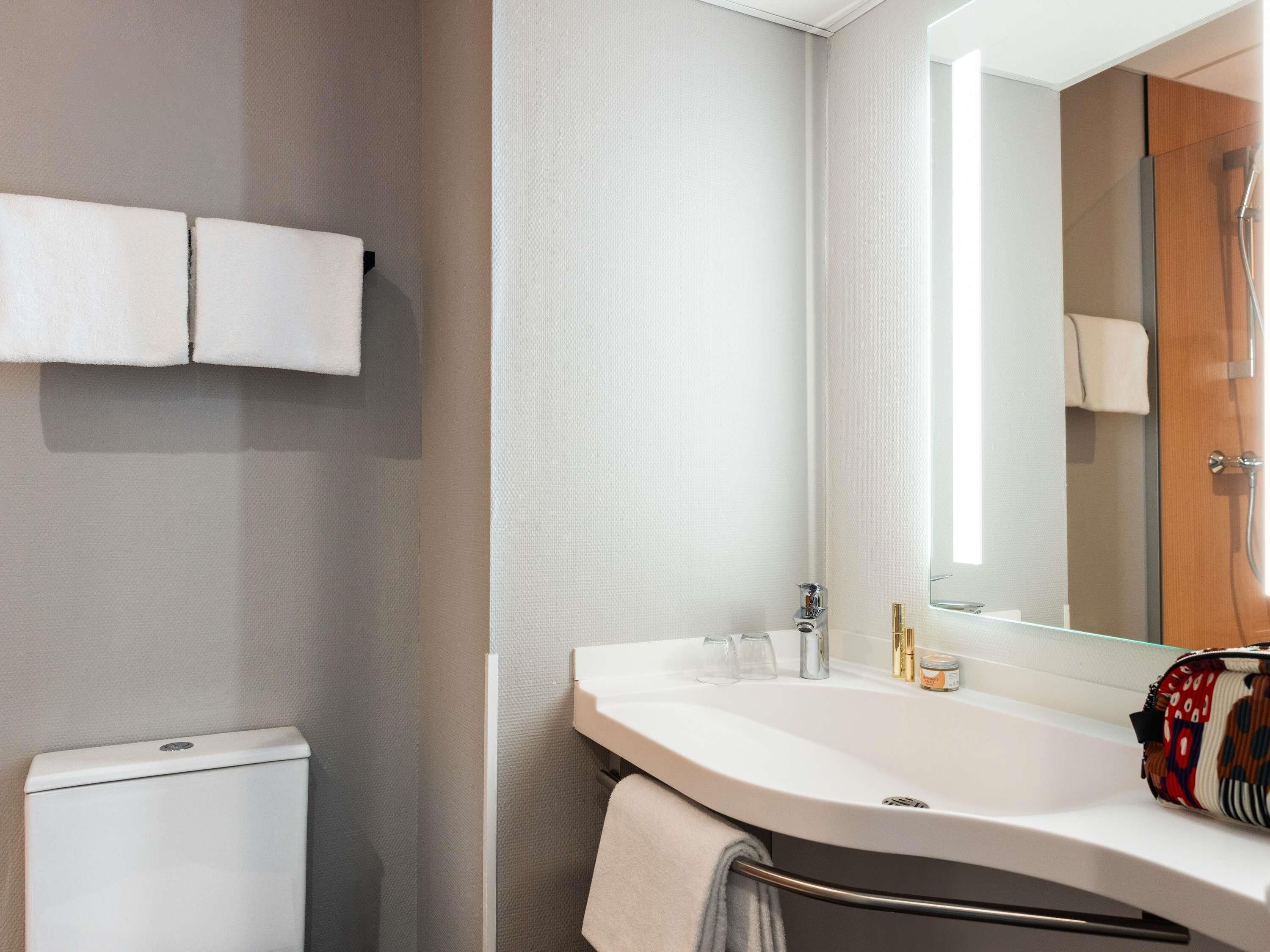 A bathroom with a white sink, a mirror, and a towel rack.