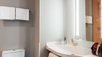 A bathroom with a white sink, a mirror, and a towel rack.