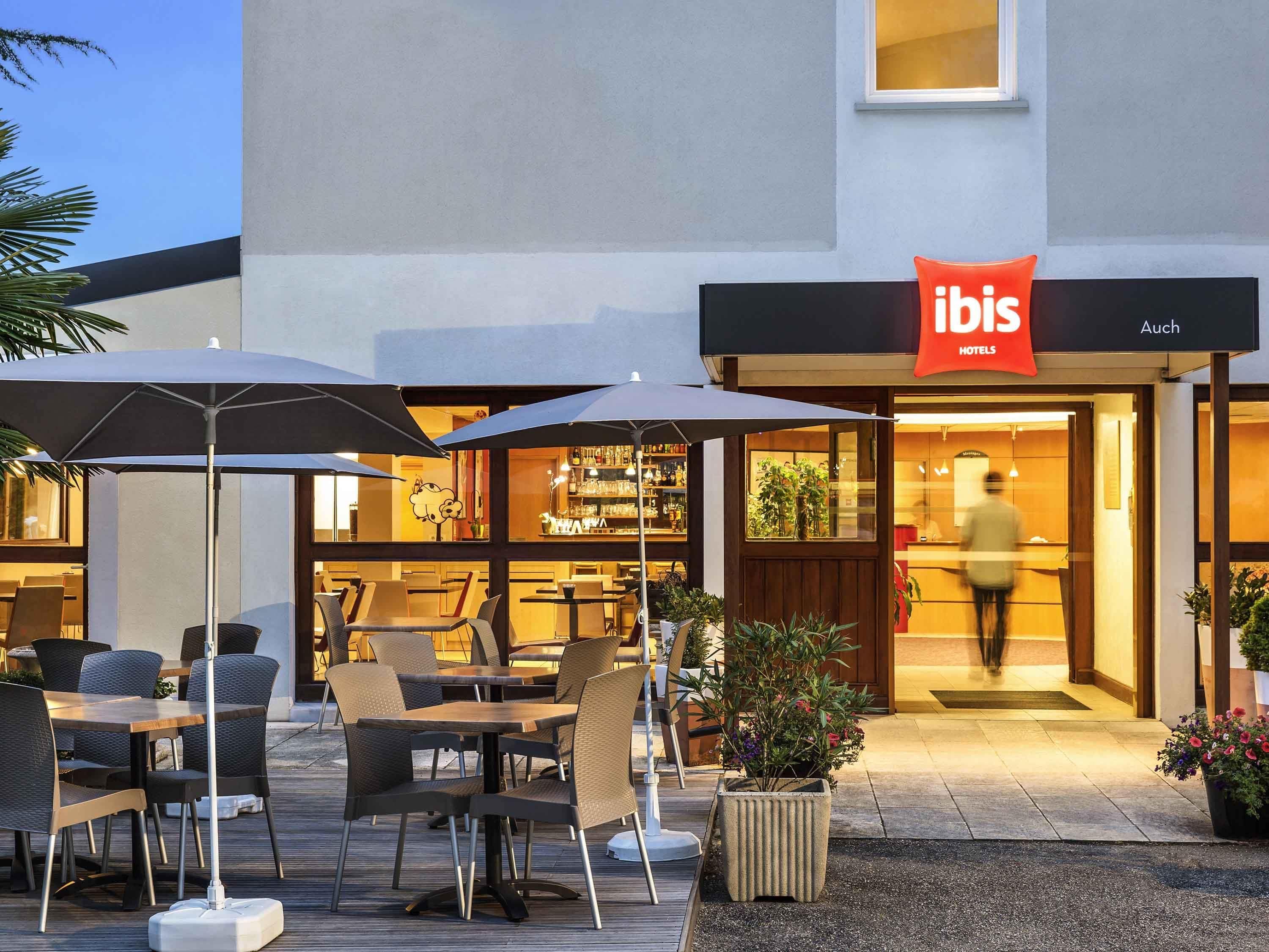 Een terras met tafels, stoelen, parasols en plantenpotten.