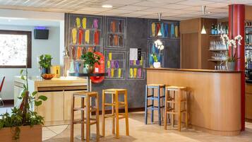 Una zona de bar con taburetes, una barra y una pared con jarrones de colores.