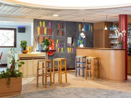 A bar area with stools, a counter, and a wall with colorful vases.