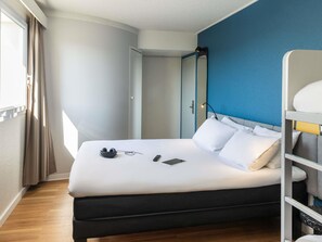 A hotel room with a bed, a bedside table, a lamp, and a window with curtains. - ibis Auch (Auch)