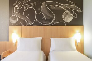 Habitación de hotel con dos camas, cabecero de madera y luces fijadas a la pared.