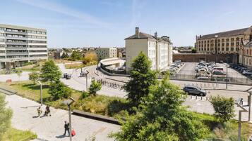 Un espace de stationnement avec plusieurs voitures, un chemin piétonnier et des bâtiments environnants.