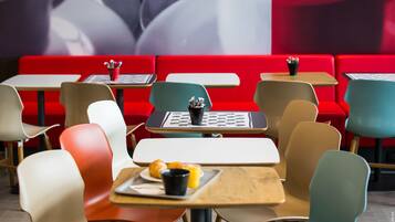Un interior de restaurante moderno con asientos rojos, varias mesas y sillas.