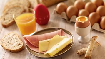 A breakfast setting with bread, eggs, cheese, and a glass of orange juice on a wooden table.