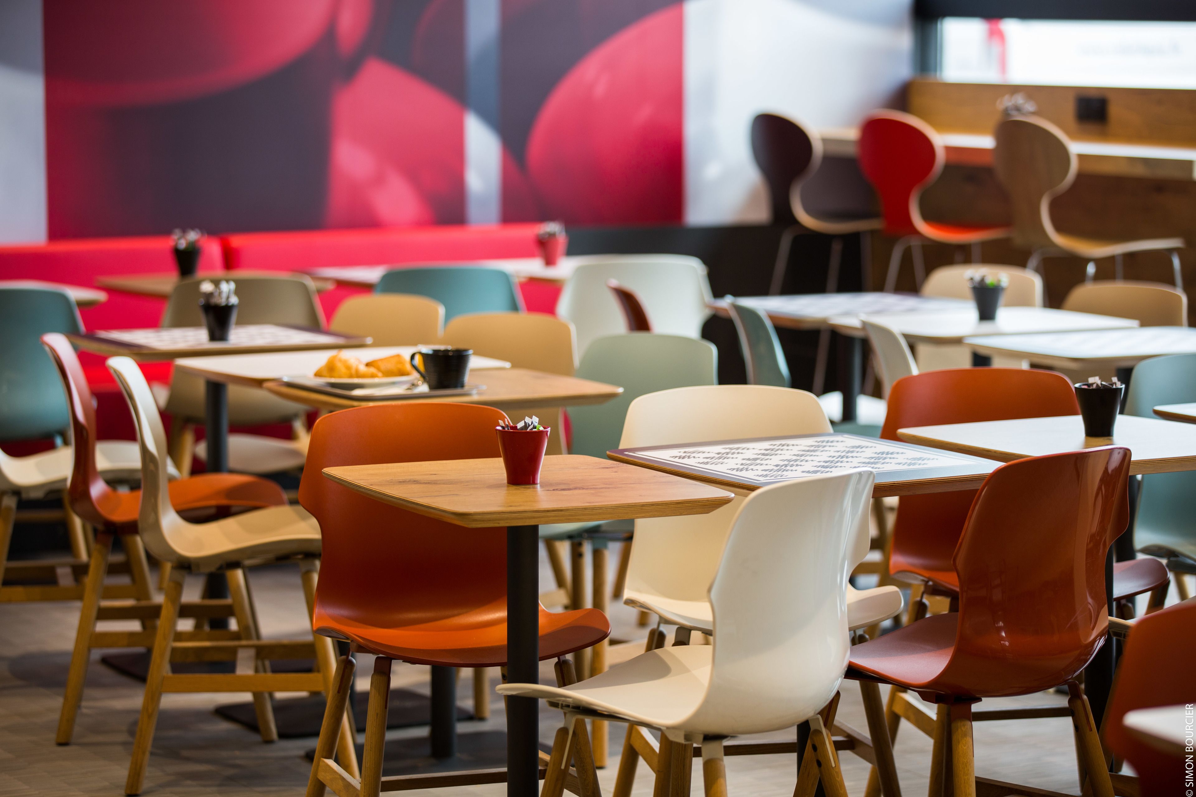 Interior modern d'un restaurant amb diverses opcions de seients, incloent taules i cadires.
