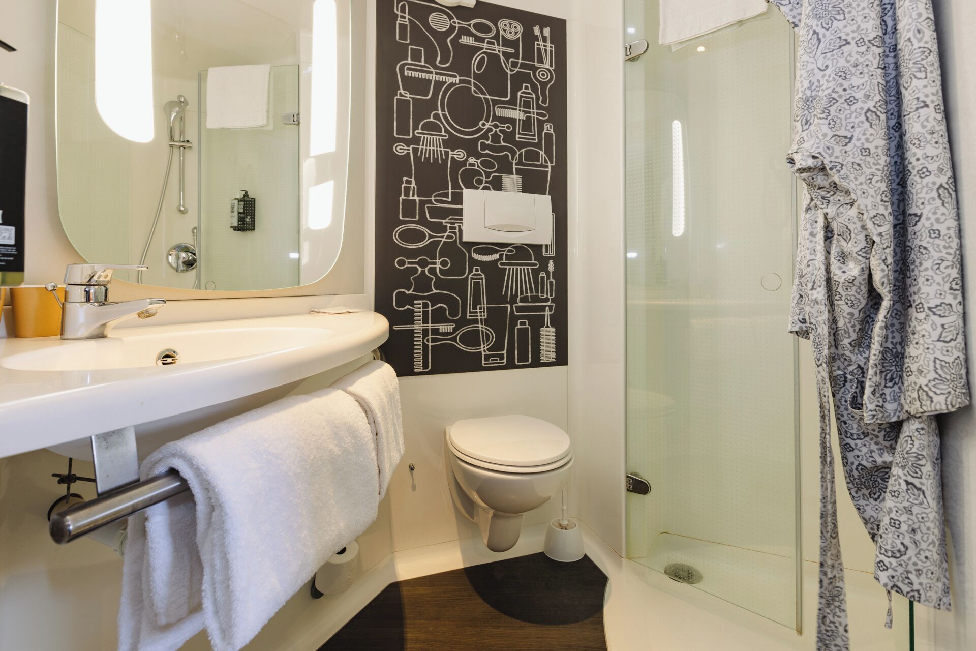Un bagno moderno con un lavandino bianco, un water e uno spazio doccia in vetro.
