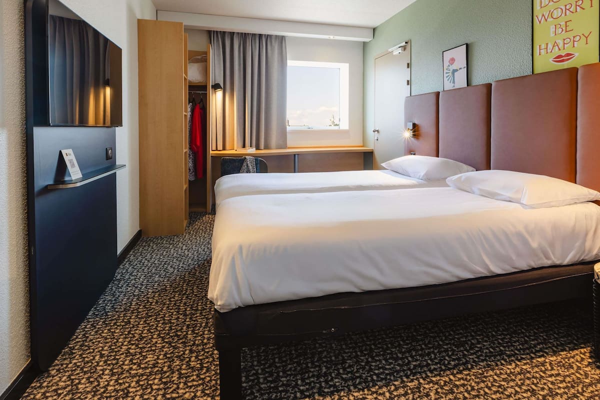 Quarto de hotel com uma cama, uma escrivaninha e um guarda-roupa.