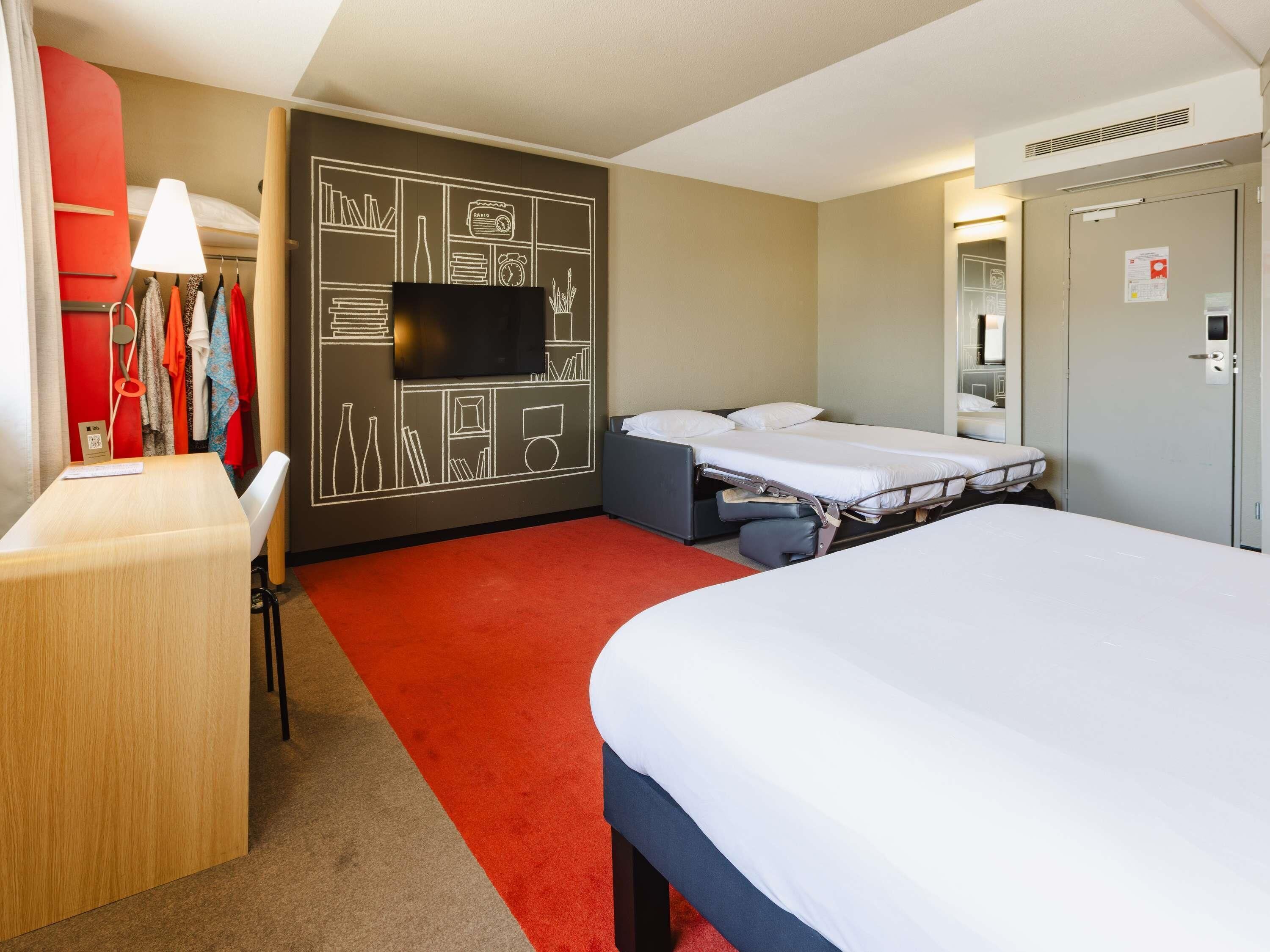 Une chambre d’hôtel équipée d’un lit, d’un bureau, d’une télévision et d’une armoire.