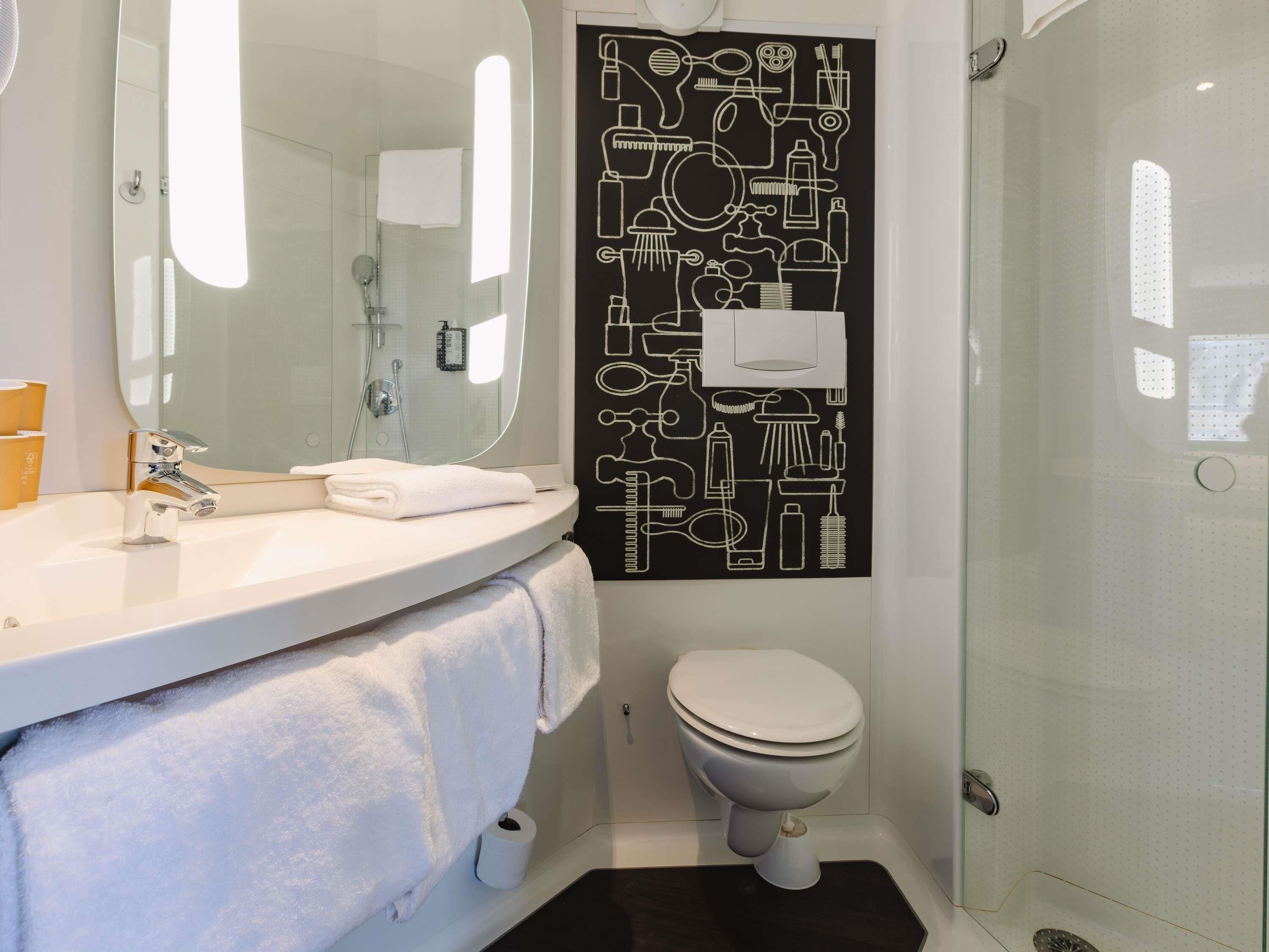 Un baño con lavamanos blanco, inodoro y cabina de ducha de vidrio.