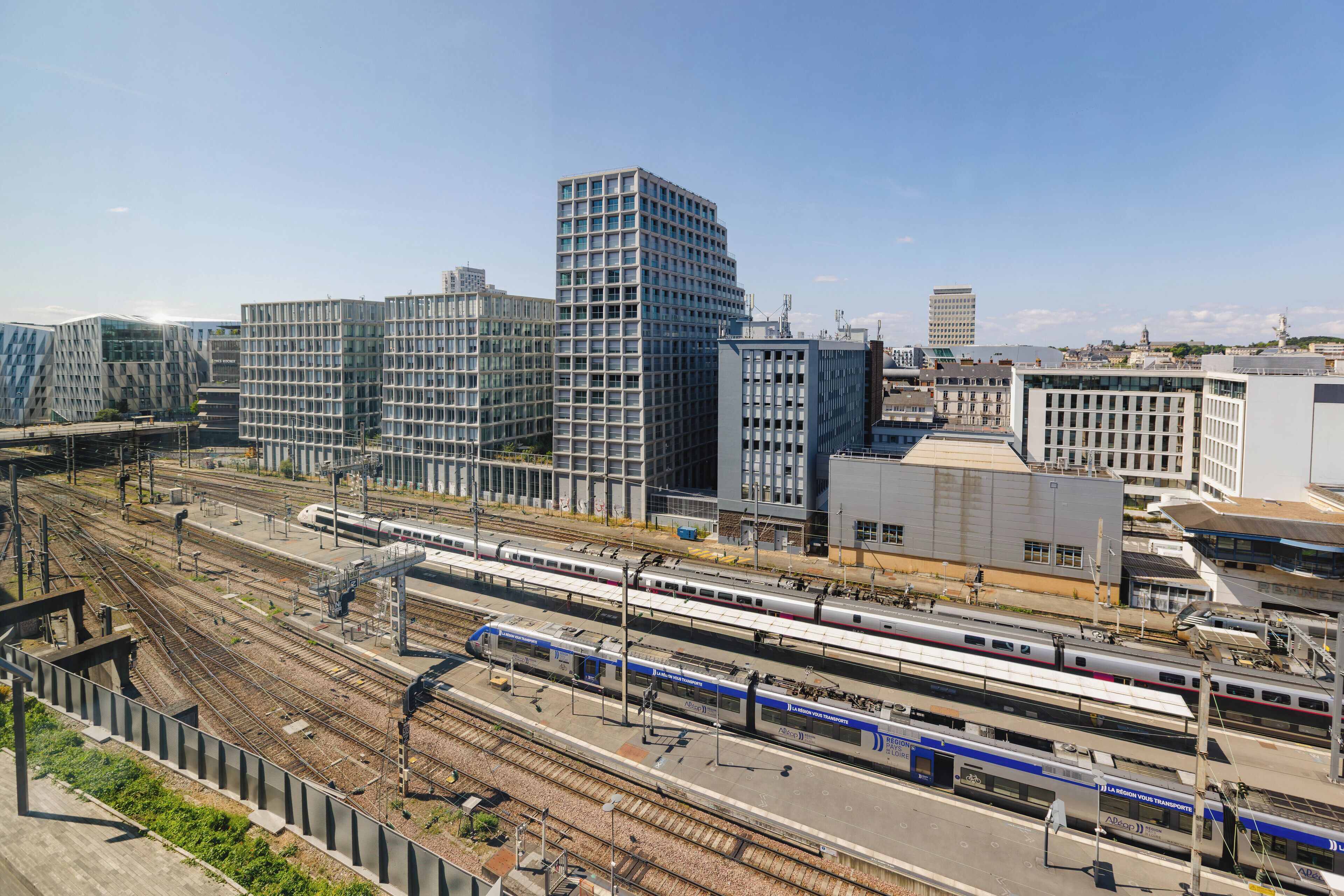 A modern urban area with multiple train tracks and high-rise buildings.