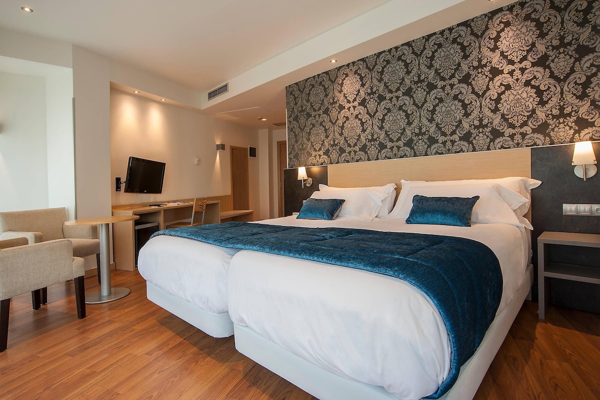 Una habitación de hotel con una cama grande, un escritorio, una silla y un televisor.