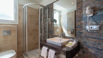 A modern bathroom with a glass-enclosed shower, a large mirror, and a sink with toiletries.