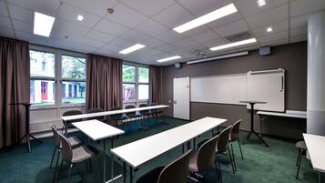 A conference room with a whiteboard, tables, and chairs.