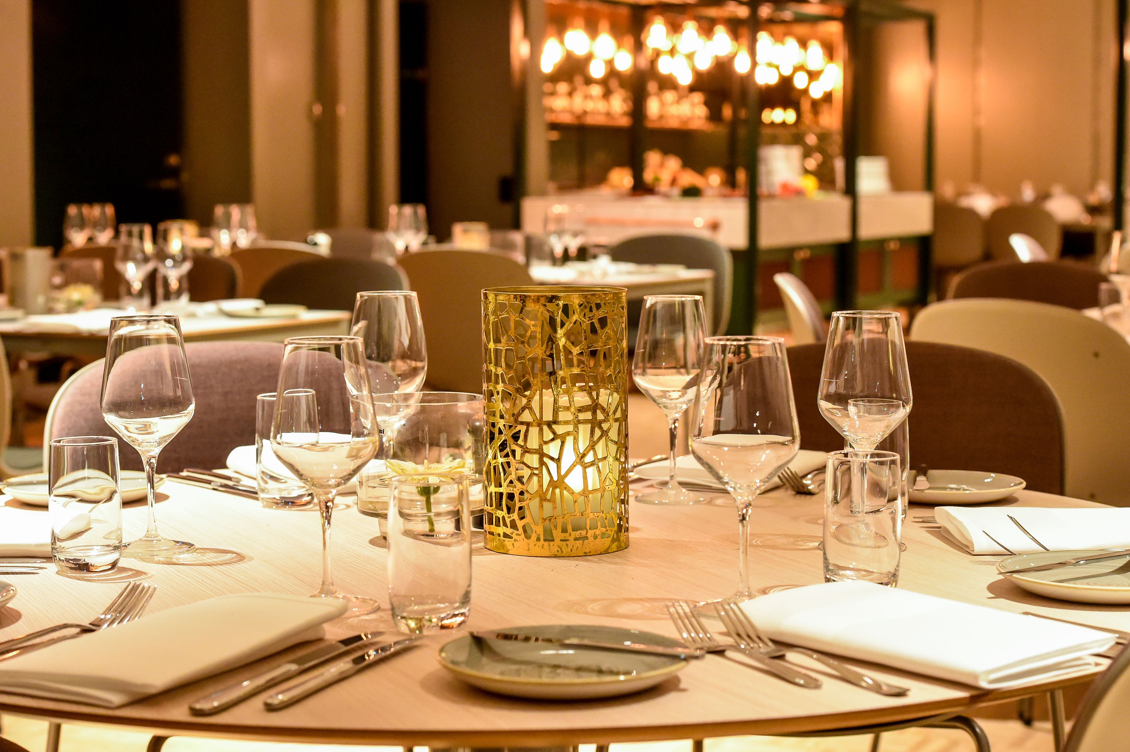 A dining table set with wine glasses, plates, cutlery, and a decorative candle holder.