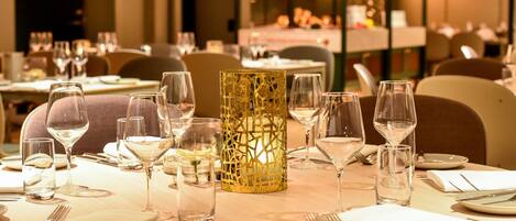 A dining table set with wine glasses, plates, cutlery, and a decorative candle holder.