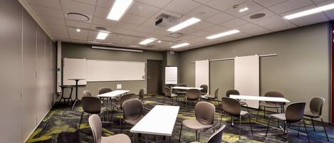 A conference room with a carpeted floor, white tables, and chairs.